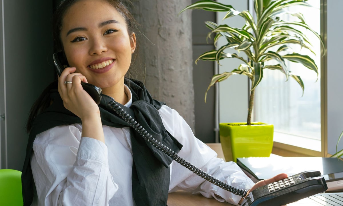 Receptionist answering a business phone at an office desk