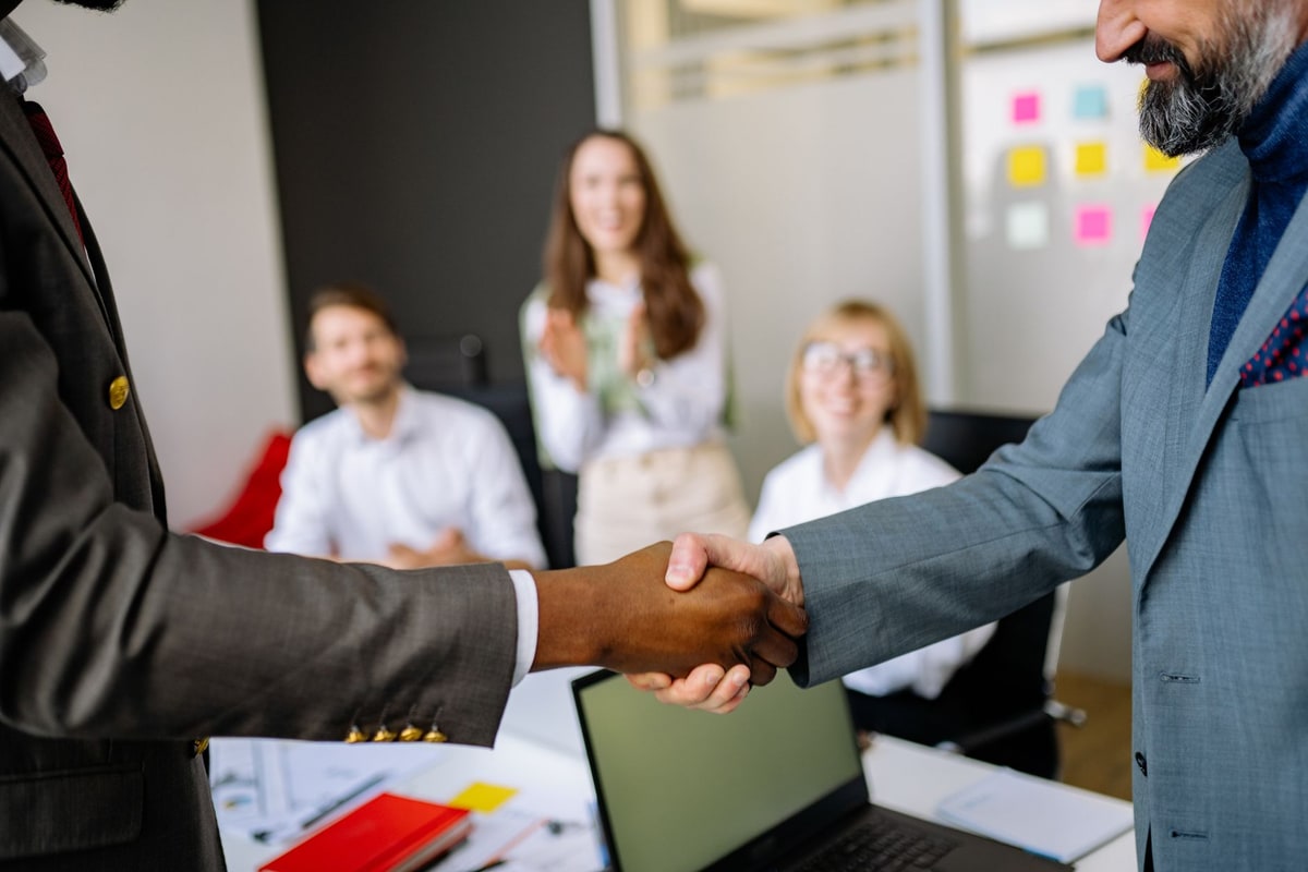 Two professionals shaking hands over a signed automation project agreement