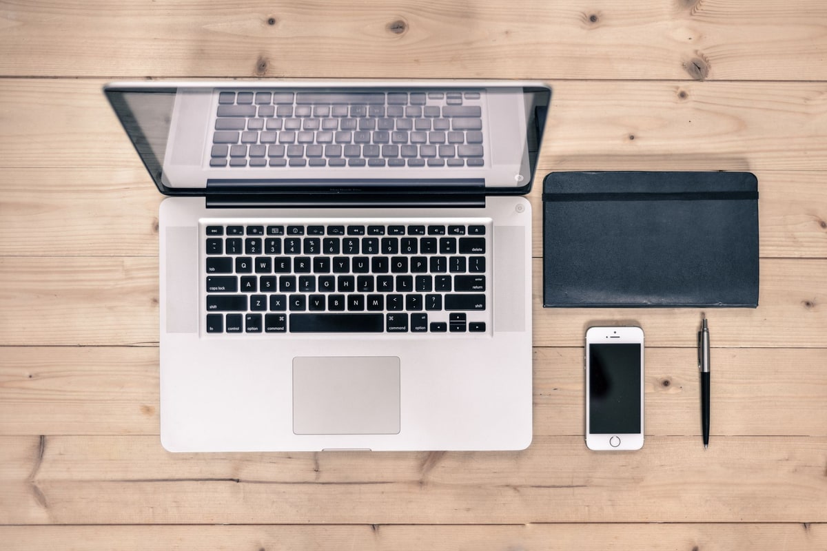 Office desk with laptop, phone, and notebook showing manual handoffs between tools
