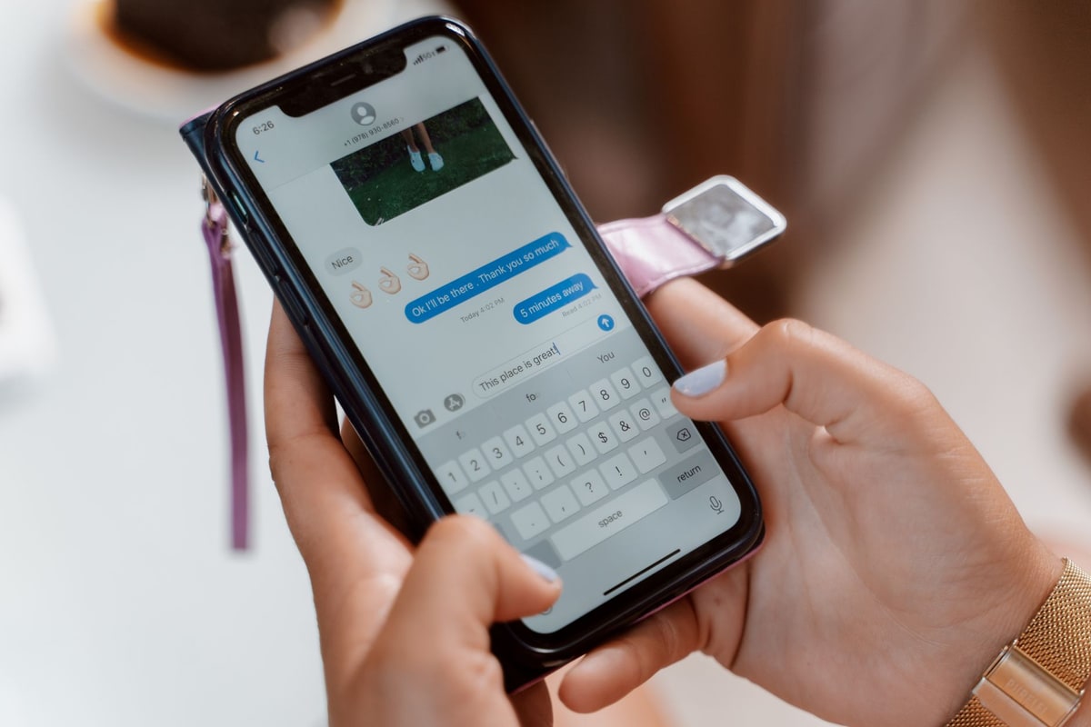 Business owner typing a text message on a smartphone at a desk