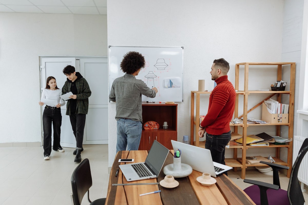 Sales team mapping routing decisions on a whiteboard beside a laptop